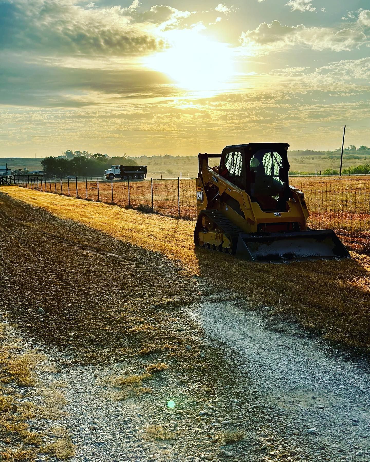 Woman in straw hat smiles, holding wine glass near a lake.