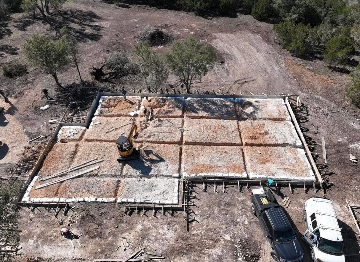 Woman in straw hat smiles, holding wine glass near a lake.