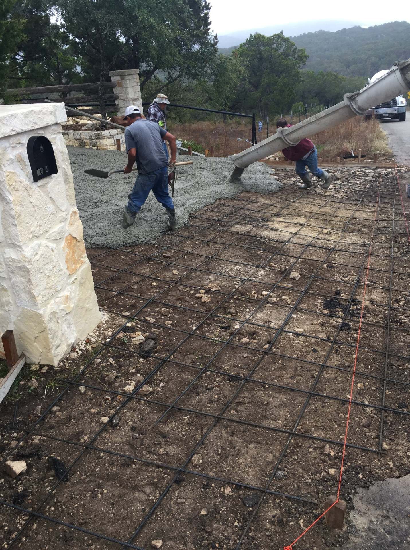 Woman in straw hat smiles, holding wine glass near a lake.