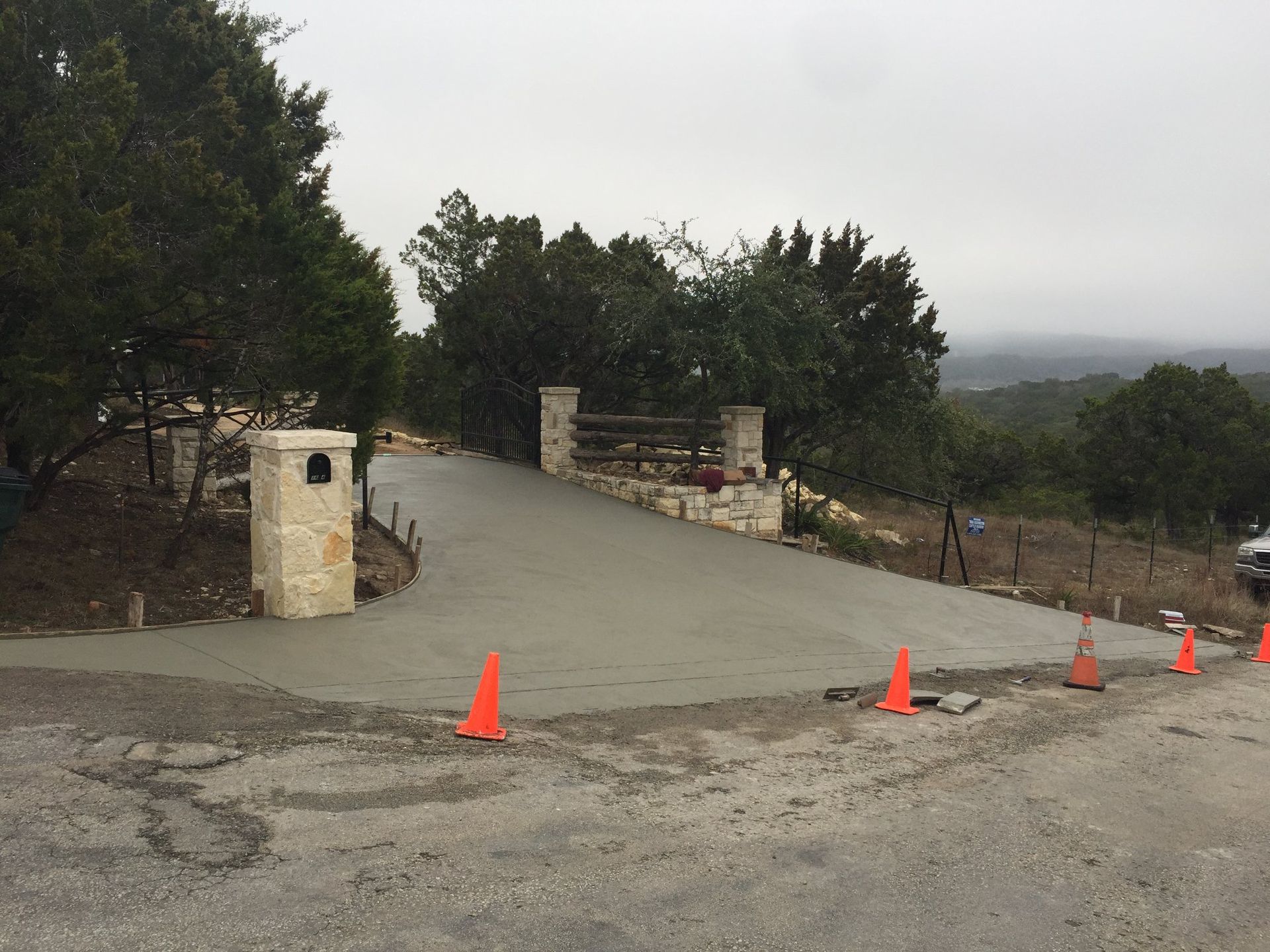 Woman in straw hat smiles, holding wine glass near a lake.