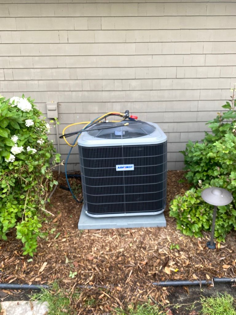 Full Time Heating & Cooling | An air conditioner is sitting on top of a pile of mulch in front of a house.