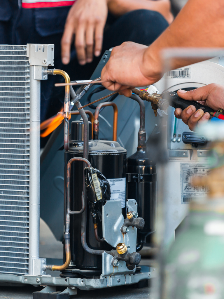 Full Time Heating & Cooling | A man is working on an air conditioner with a wrench.
