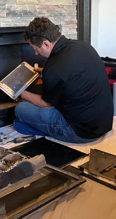 Full Time Heating & Cooling | A man is sitting on the floor in front of a fireplace looking at a tablet.