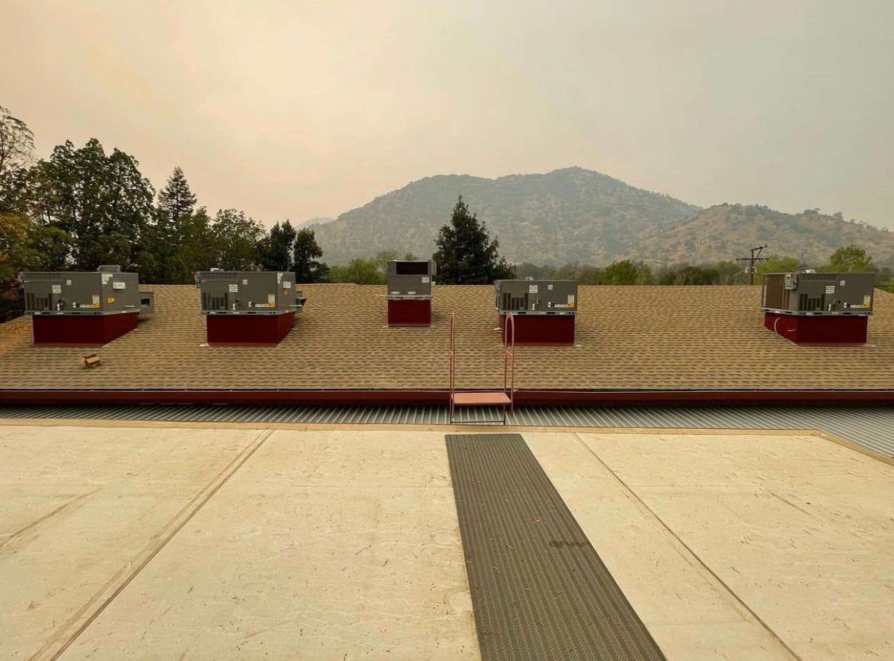Rooftop view of a building with several rooftop structures against a hazy mountain backdrop.