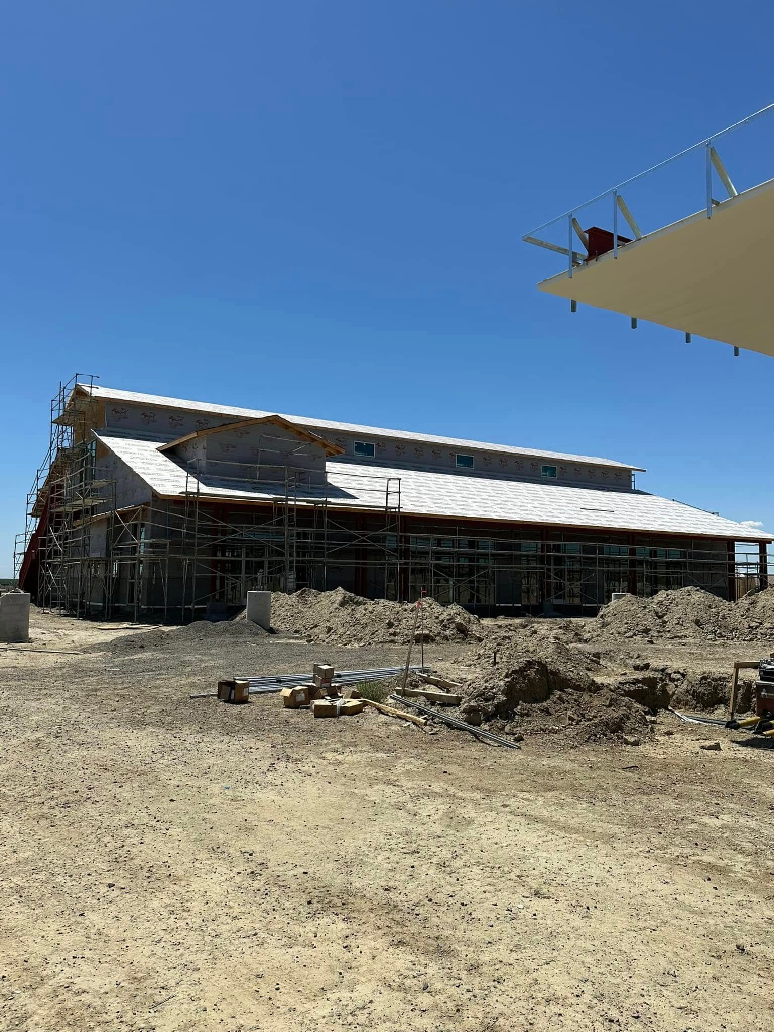 Building under construction in a desert environment with scaffolding and clear blue sky.