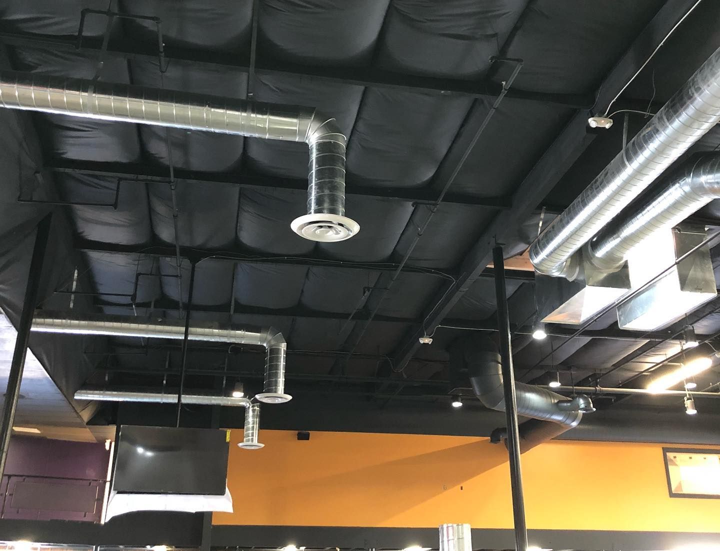 Black ceiling with exposed HVAC and lighting. Yellow and purple walls.
