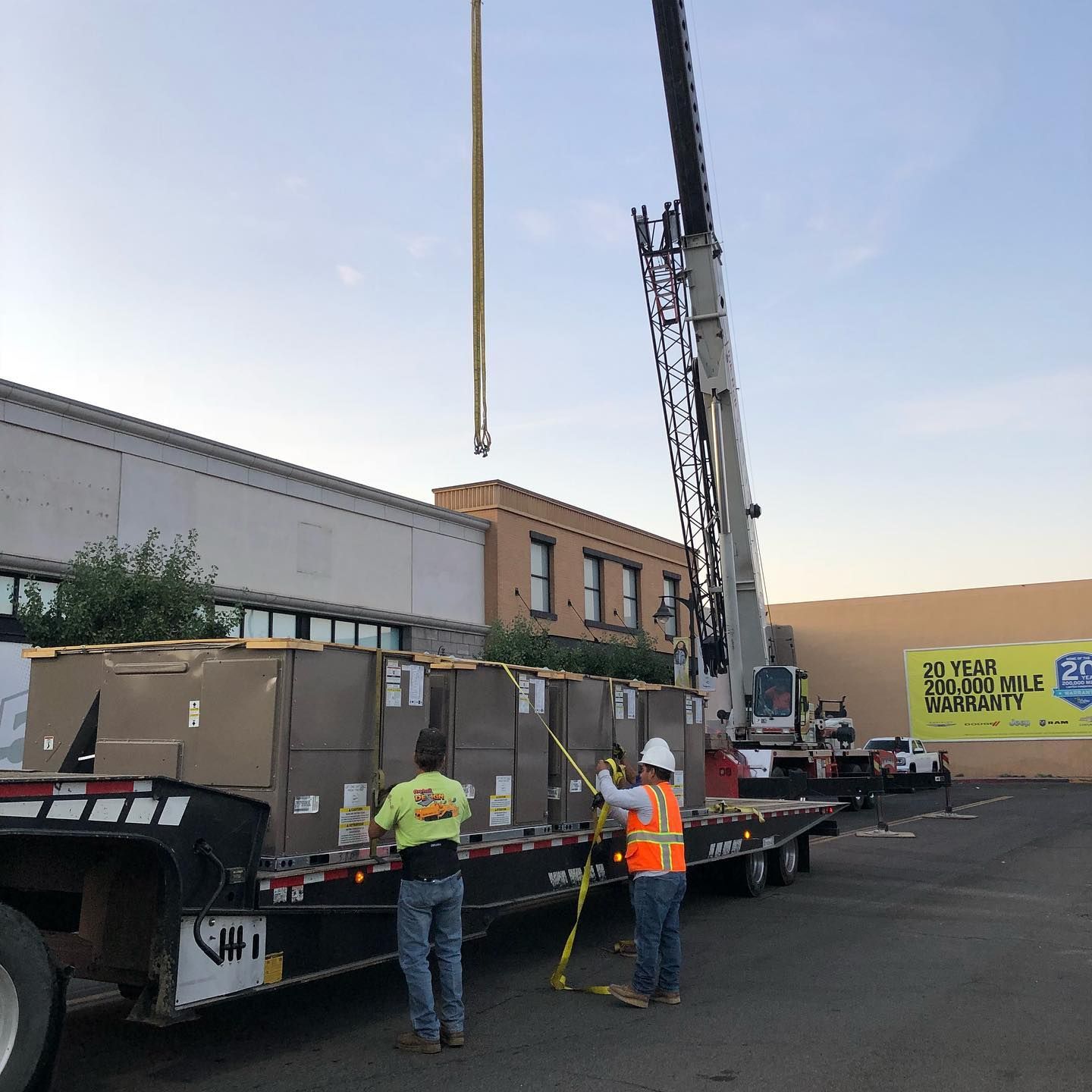 Crane lifting boxes off a truck; workers in safety vests; industrial setting.