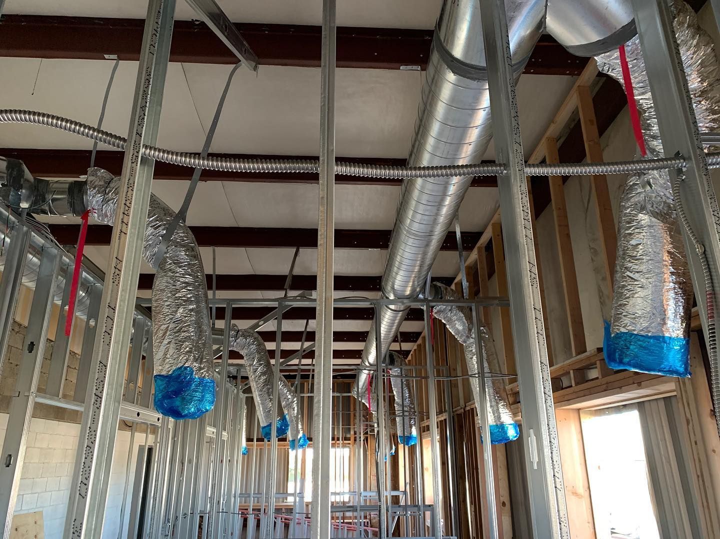 Metal framework of a building under construction, with ductwork and insulation visible.