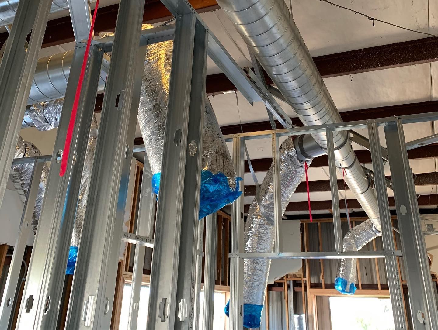 Metal studs frame construction with silver ductwork and blue tape.