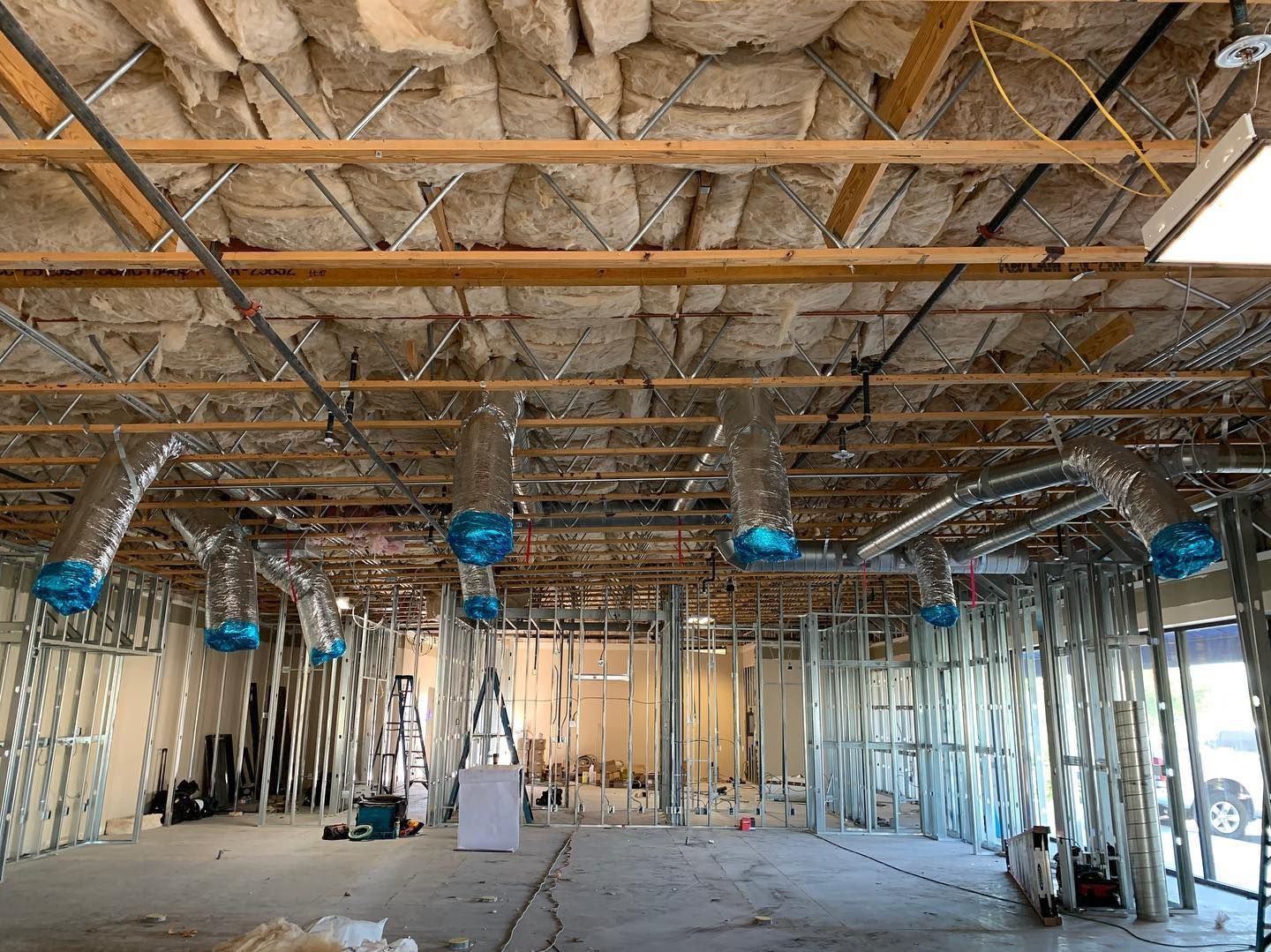 Interior of a building under construction, showing metal framing, ductwork, and insulation.