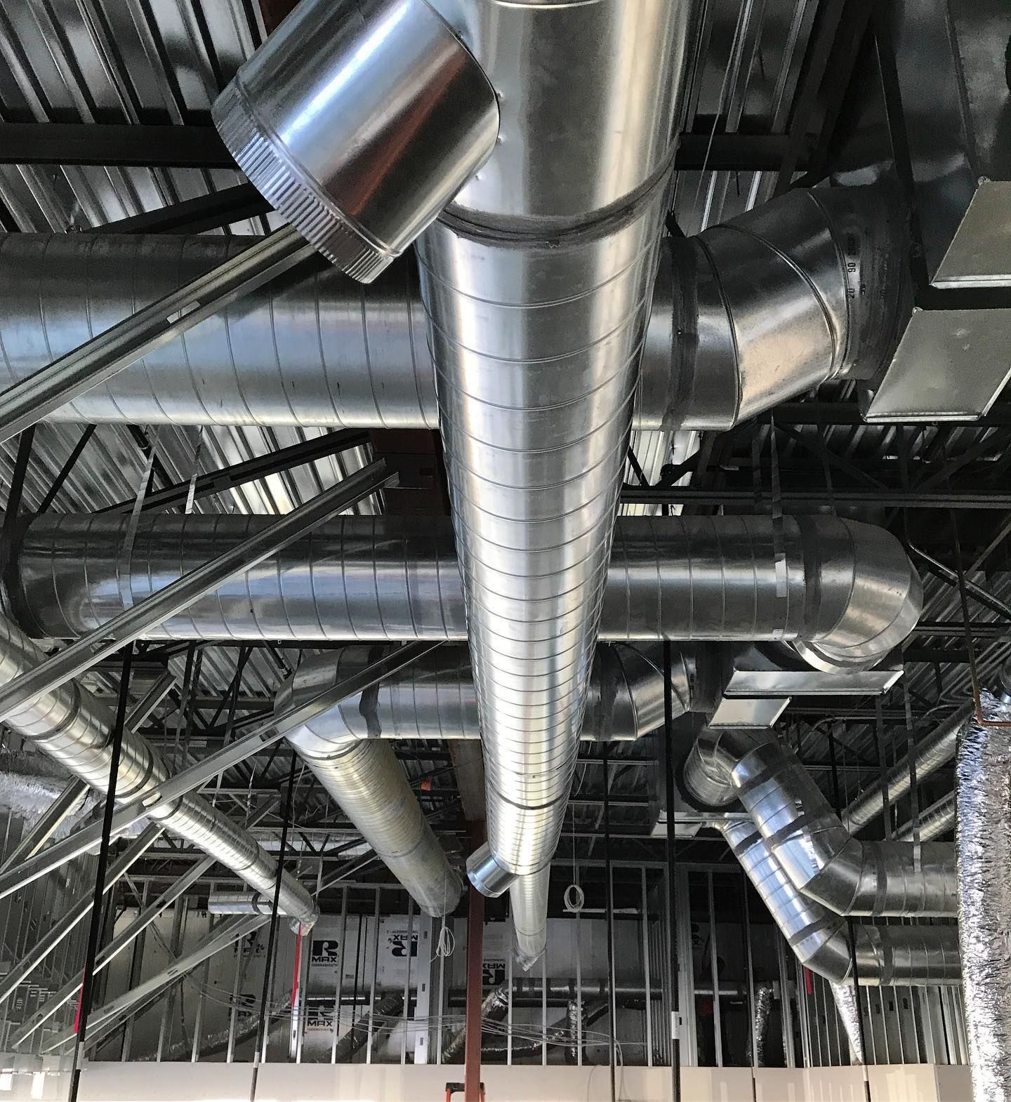 Metal ductwork installed in an unfinished building ceiling.
