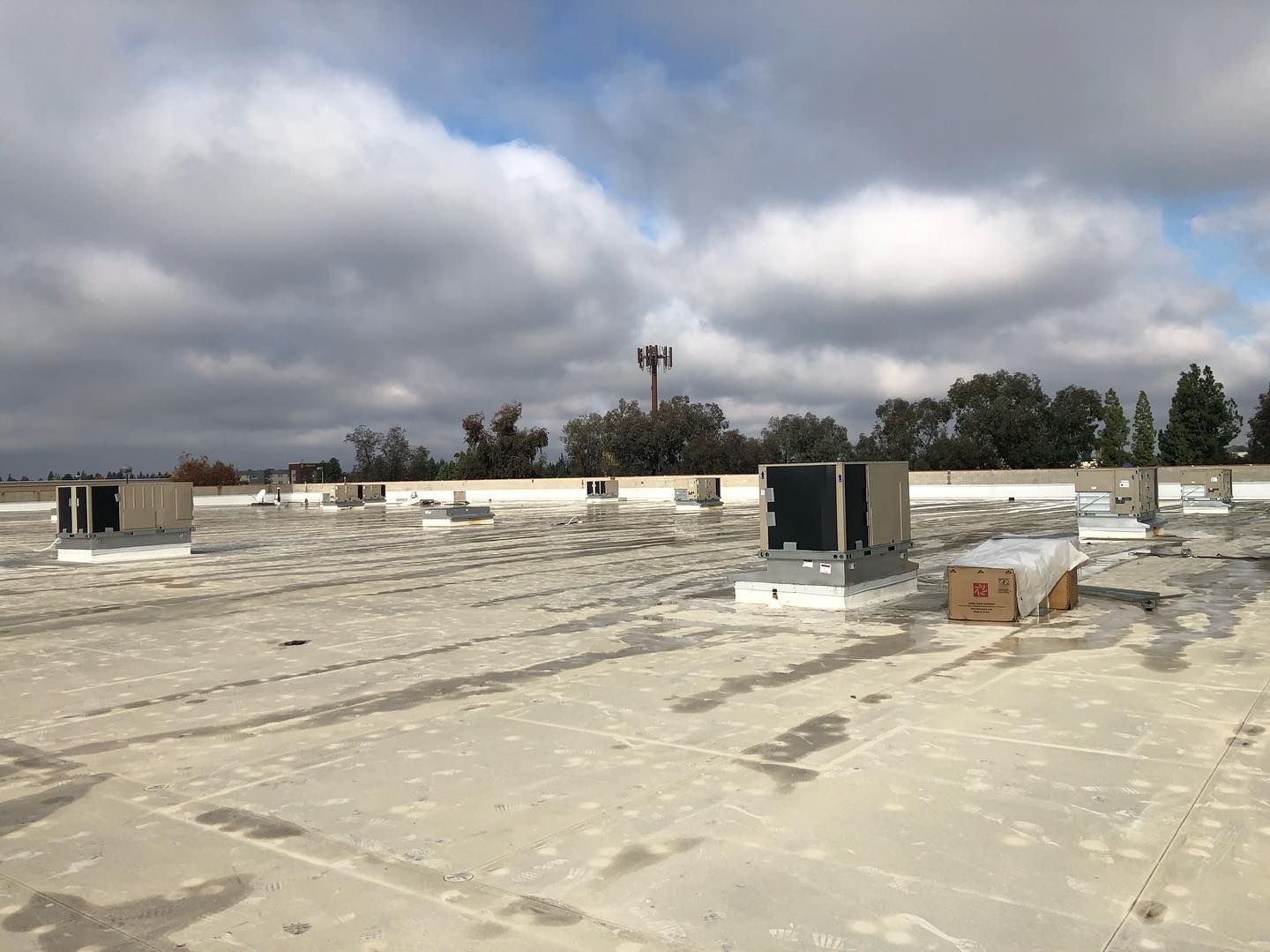Flat commercial roof with HVAC units under a cloudy sky.