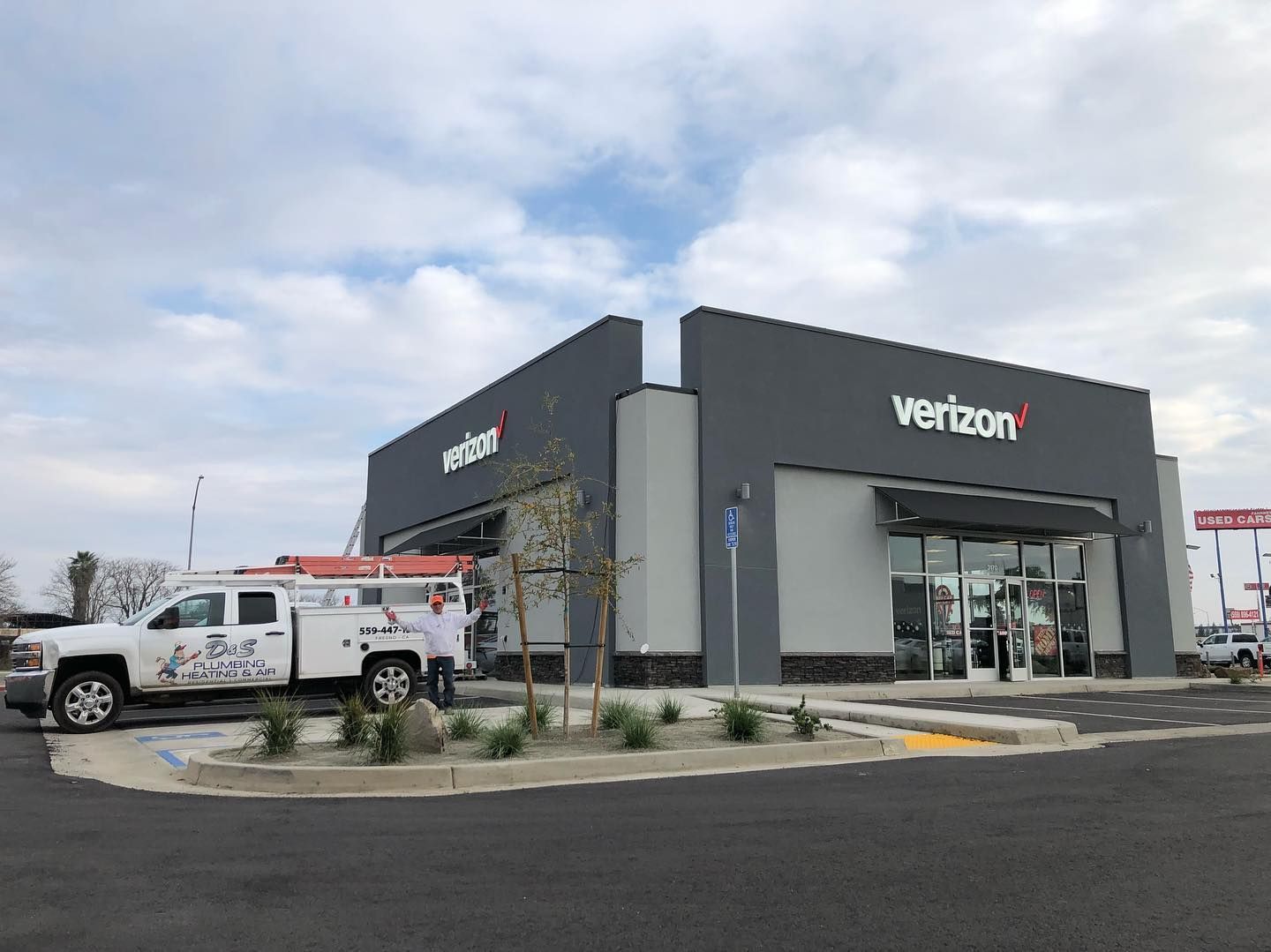 Verizon store exterior with gray facade, white sign, and service truck parked outside.
