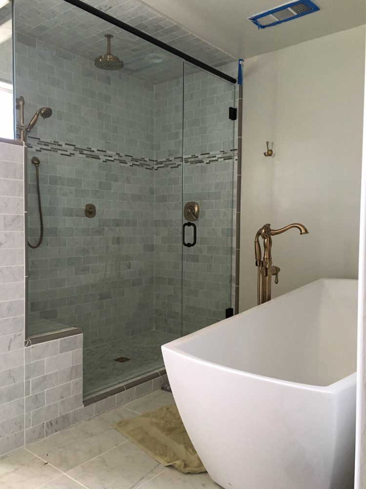 Bathroom with a glass shower enclosure and a freestanding bathtub; gold fixtures.