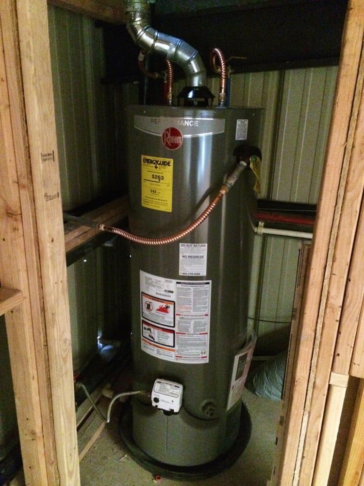 A Rheem water heater installed within a wooden frame, with a vent pipe and copper tubing.