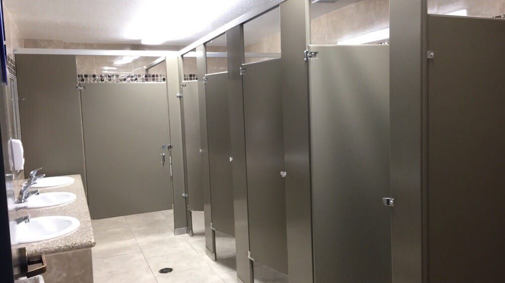 Public restroom with gray stalls, sinks, and a tiled accent.