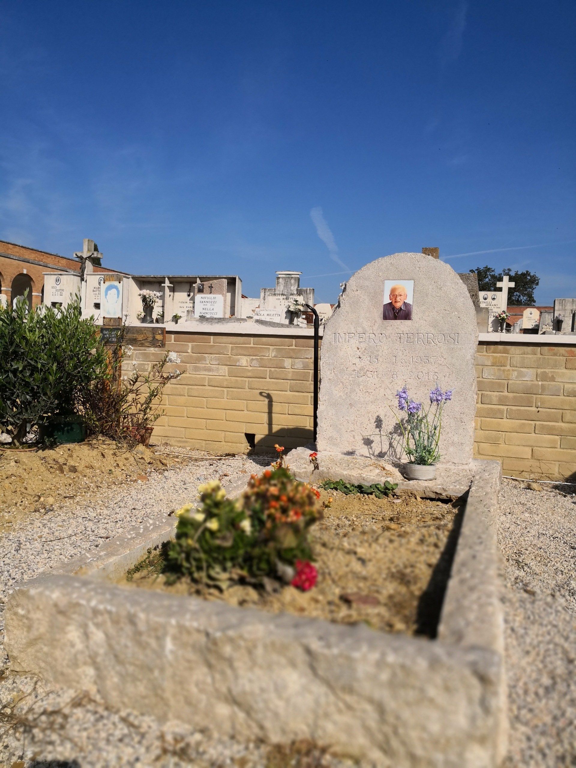 Una tomba con l'immagine di un uomo in un cimitero.