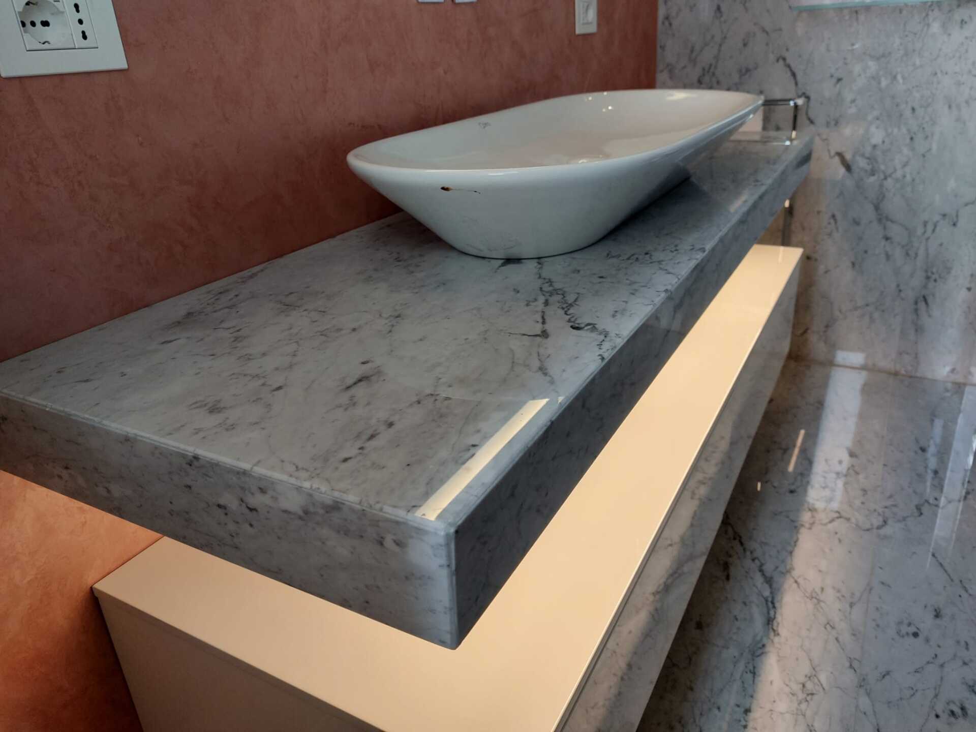 Un lavandino del bagno è appoggiato su un ripiano di marmo