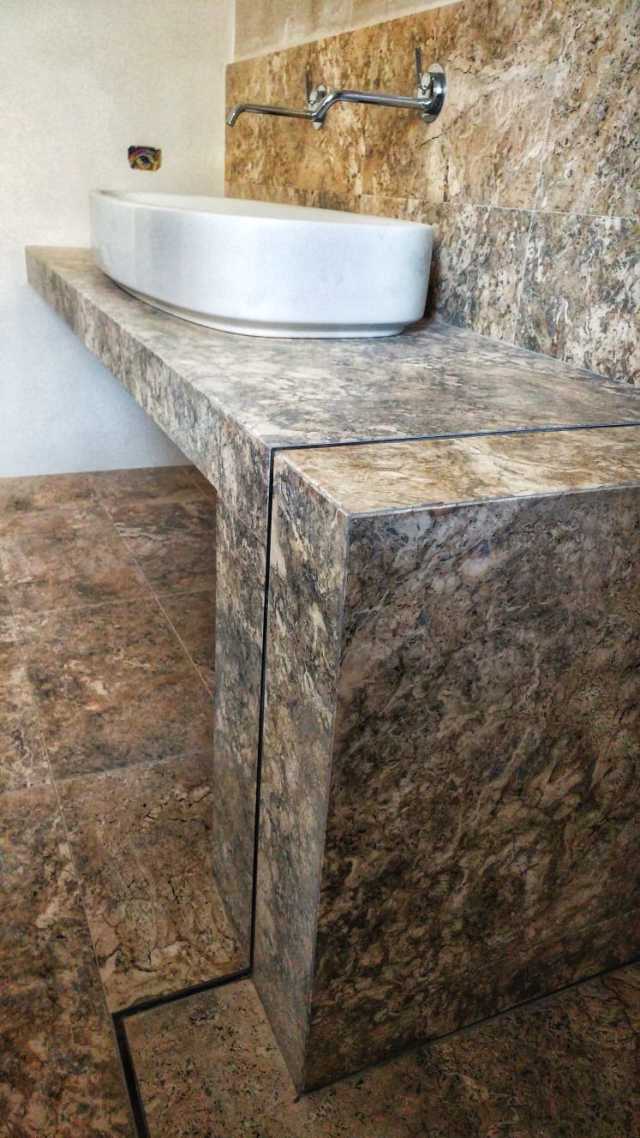 Un bagno con lavandino e ripiano in marmo.