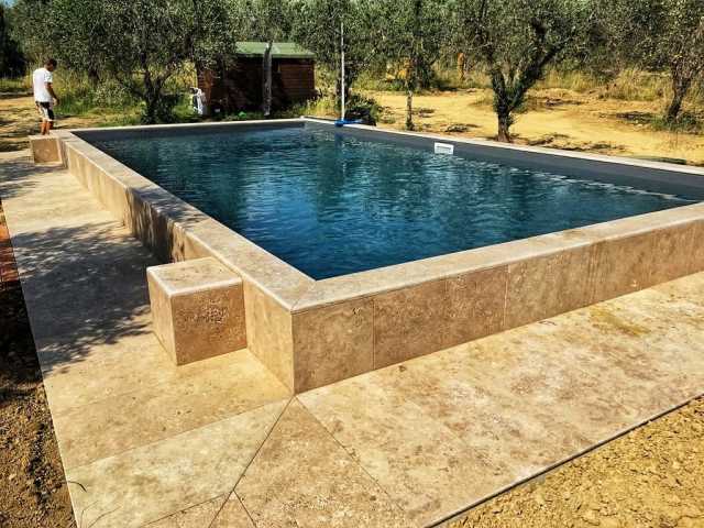 Un uomo è in piedi accanto a una grande piscina circondata da alberi.