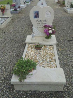 Una tomba con una lapide a forma di cuore e fiori sopra