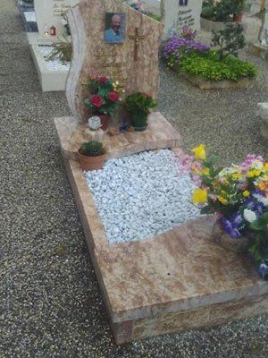 Una tomba con fiori e ghiaia in un cimitero.
