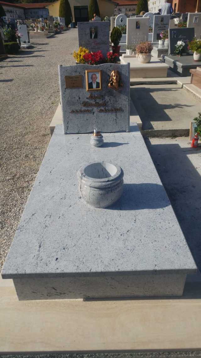 Una tomba in un cimitero con un vaso sopra.