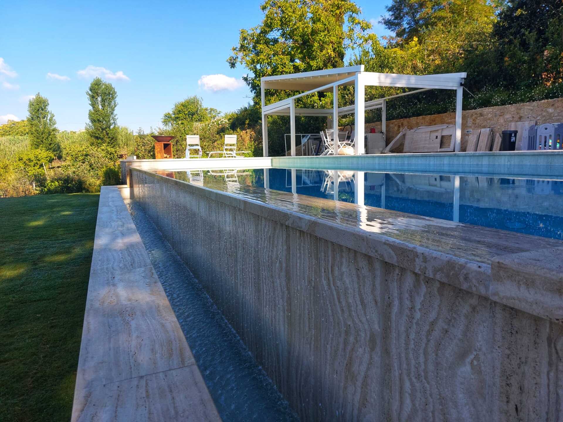 Una grande piscina con pergolato e sedie intorno