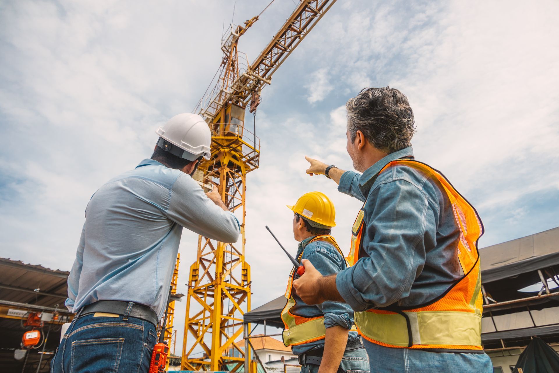 Technicians performing a safety inspection on an overhead crane at a construction site.