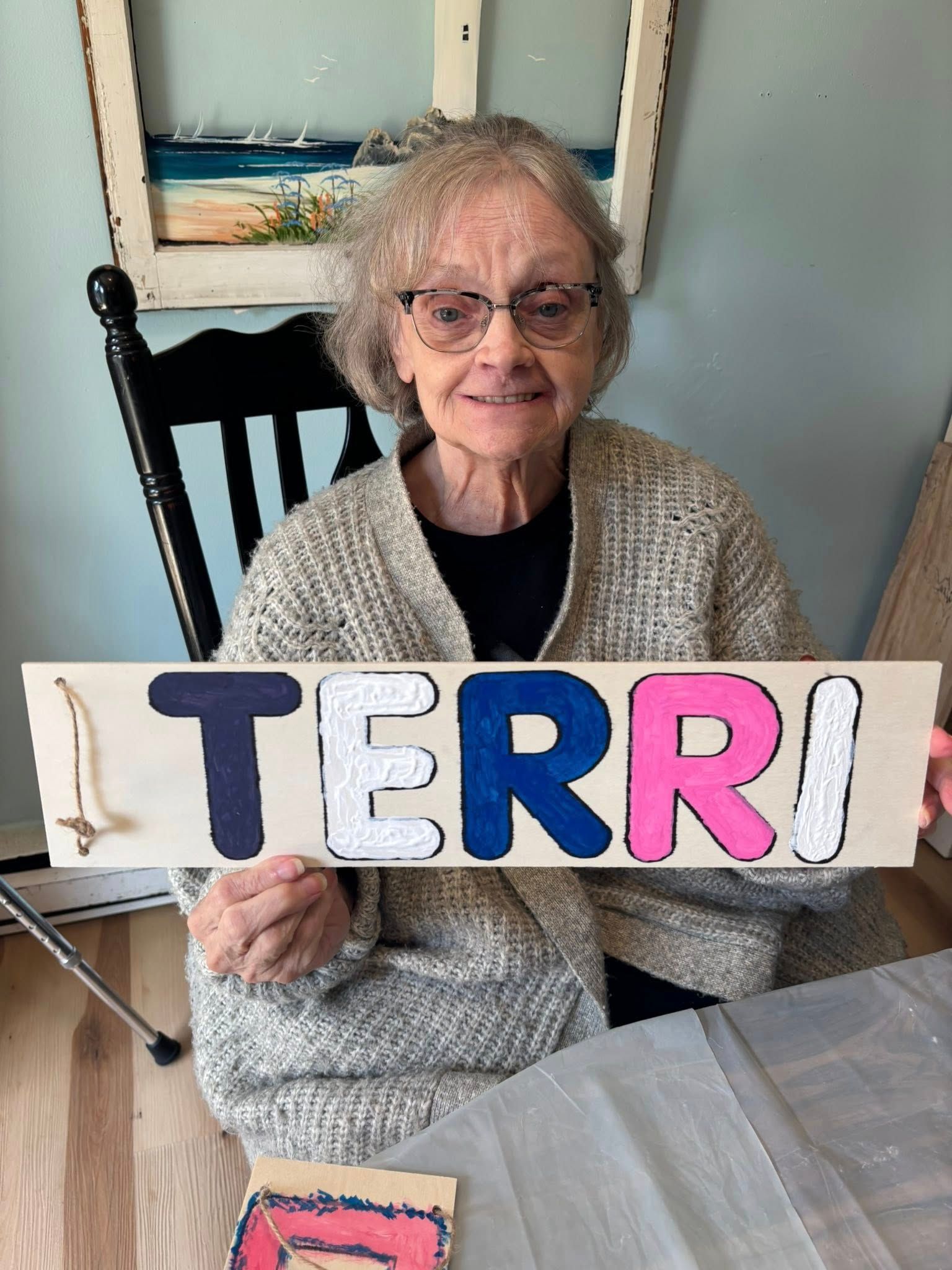 Elderly woman holds a wooden sign with