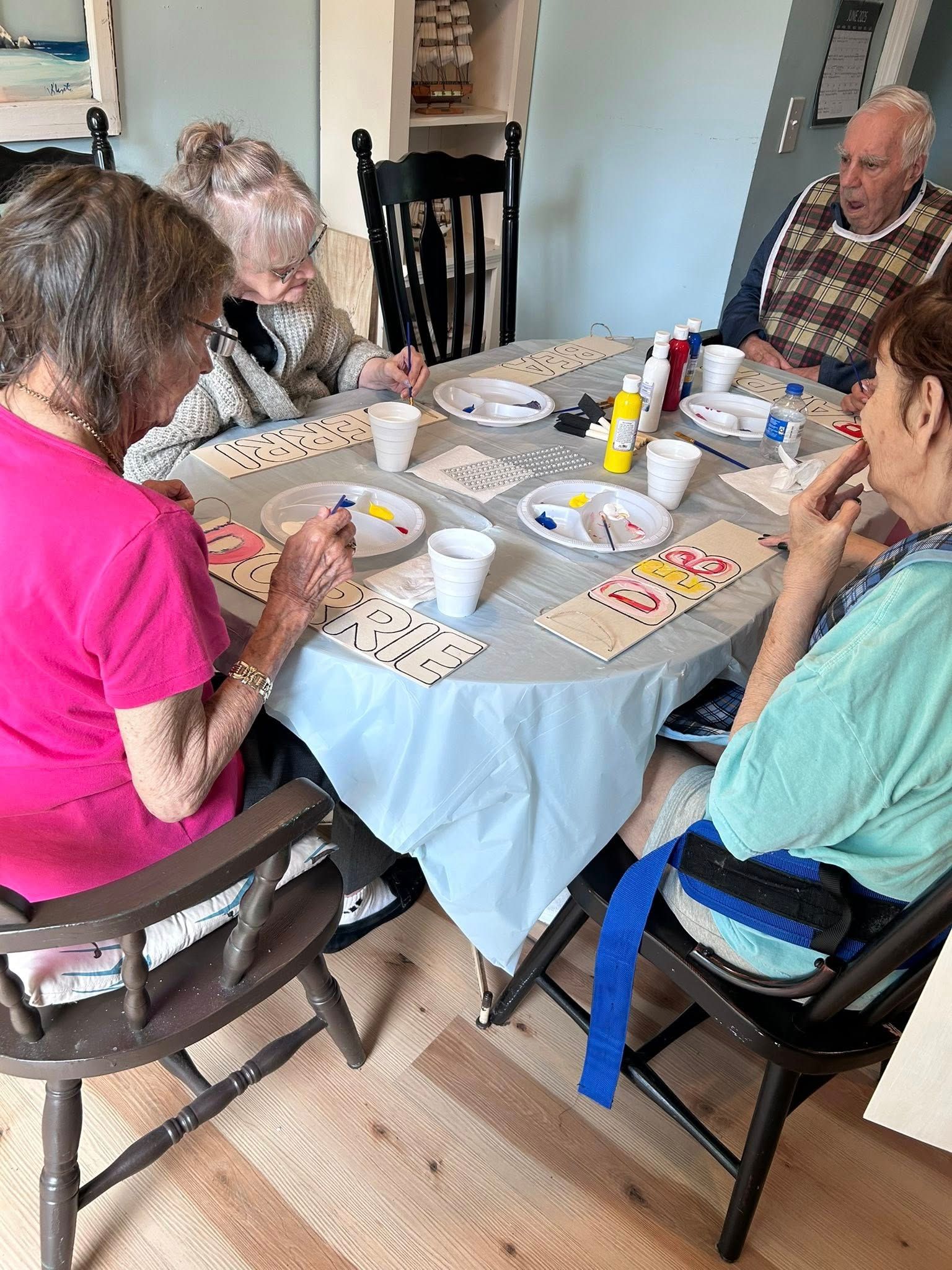 Group of seniors painting dominoes at a table.