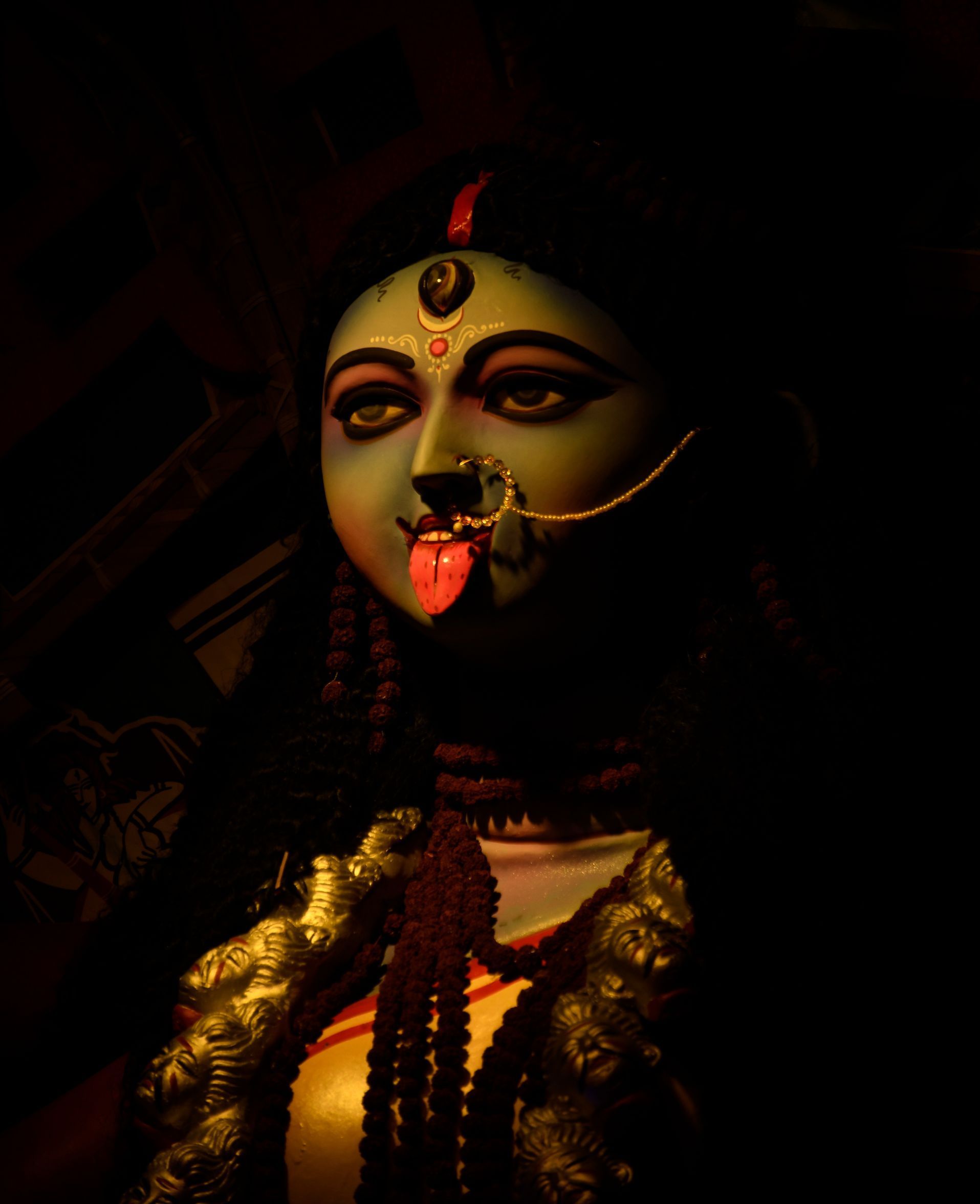 a close up of Hindu Goddess Mahakali with a red tongue sticking out of her mouth .