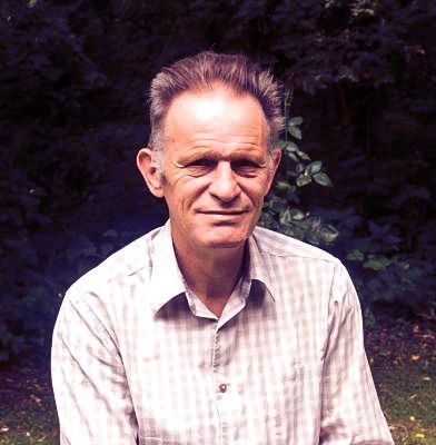 A man in a plaid shirt is sitting in the grass