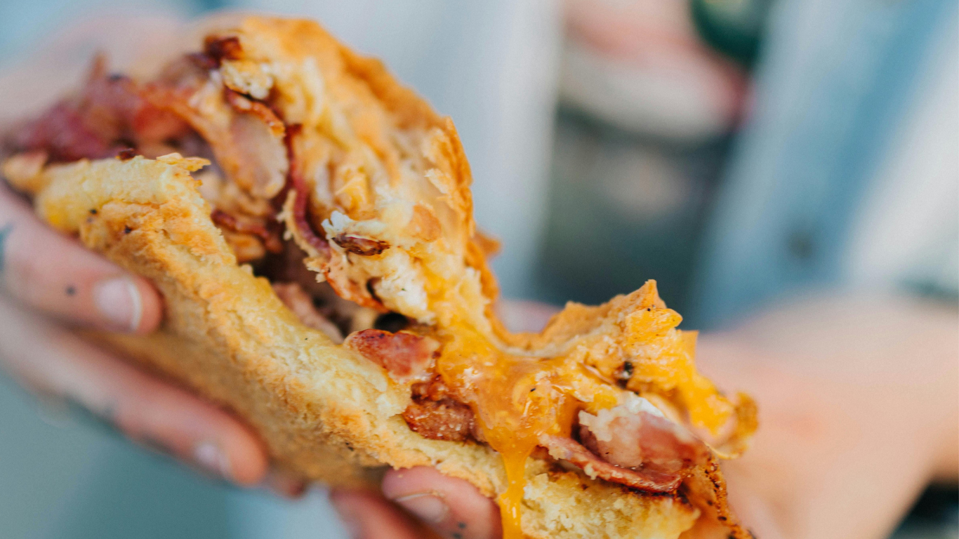 Syrup is being poured on a stack of waffles