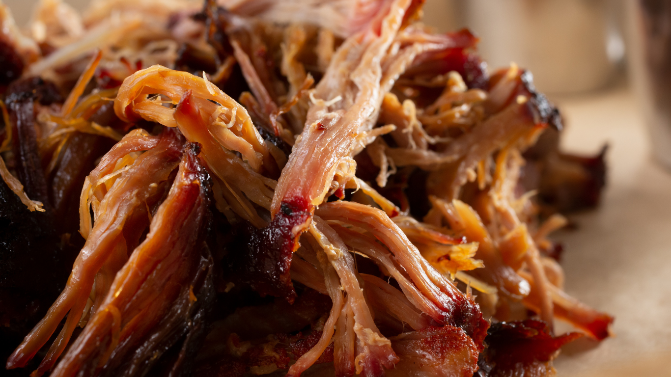 A close up of meat cooking on a grill with flames.