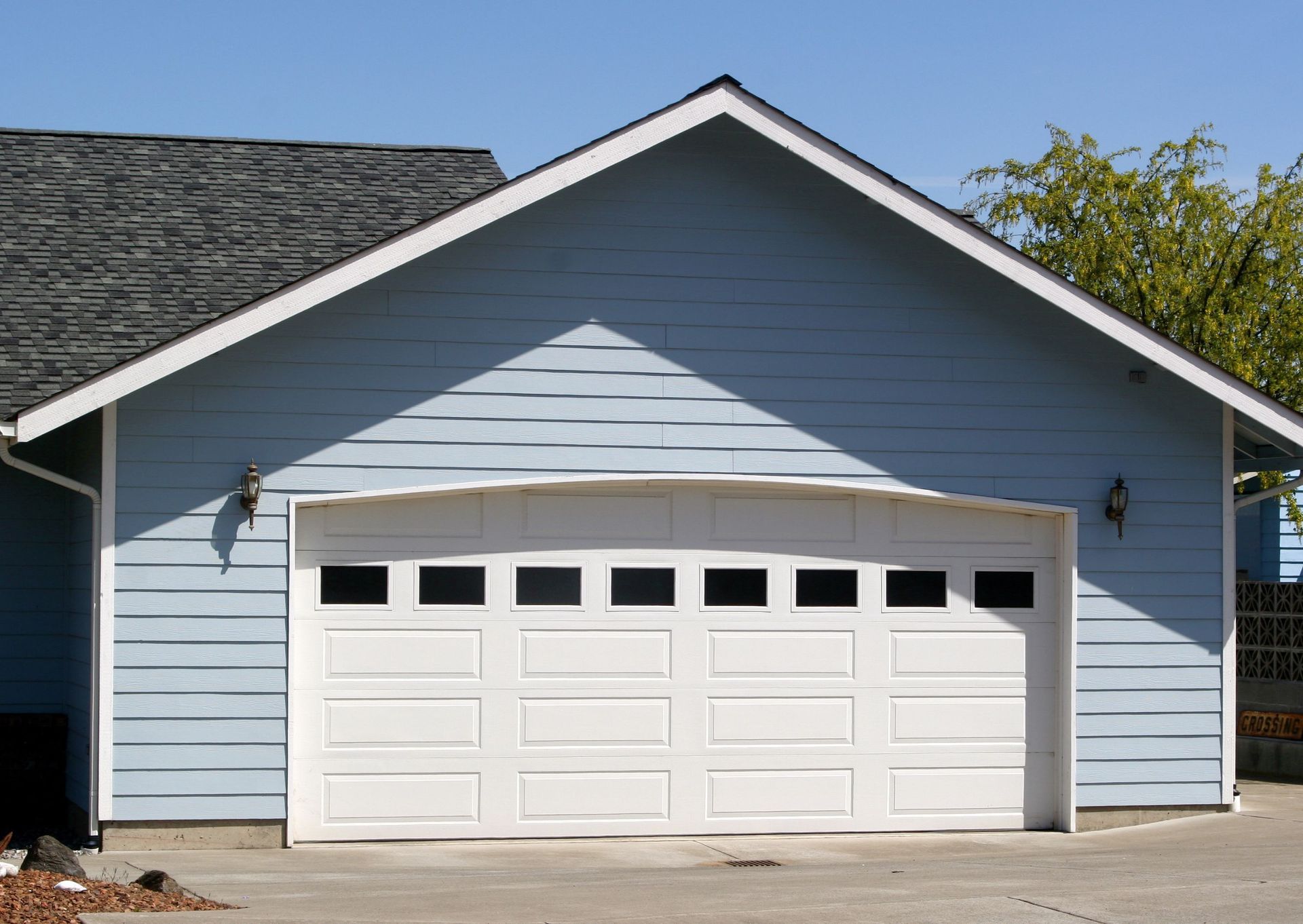 Blue house with white garage door and a dark roof.