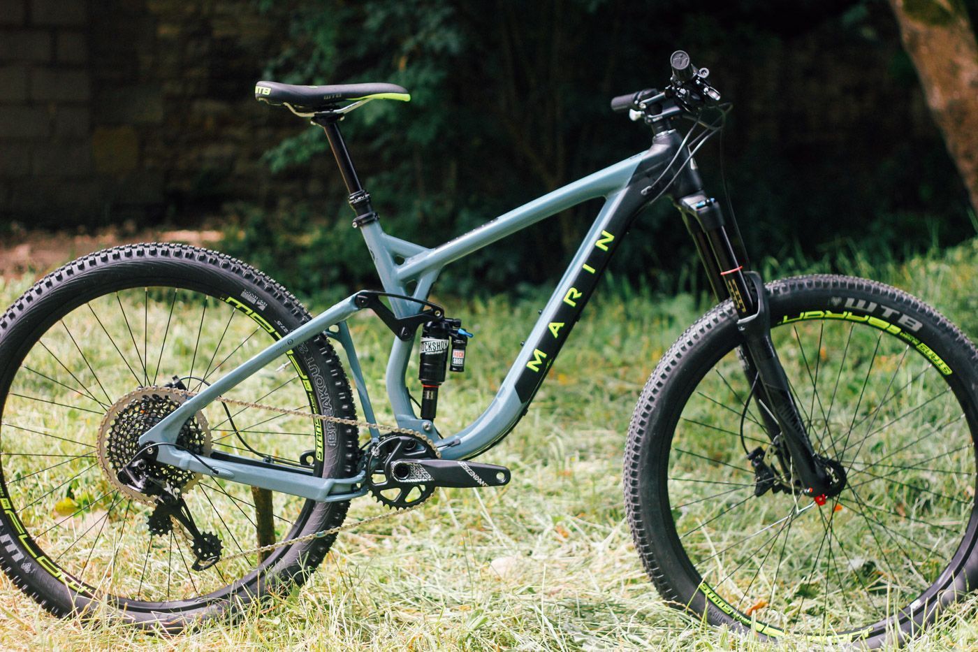 A blue mountain bike is parked in the grass.