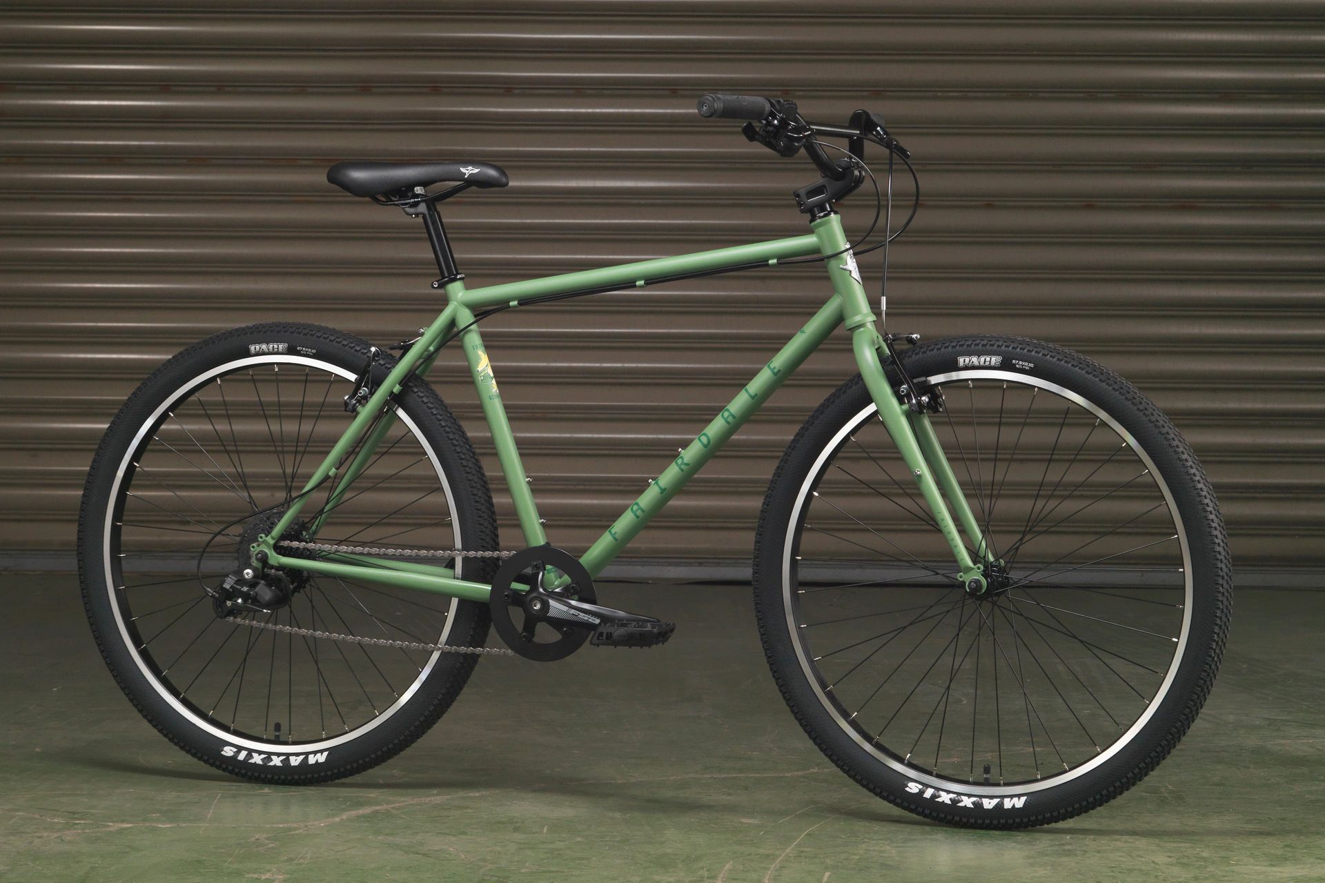 A green bicycle is parked in front of a garage door.