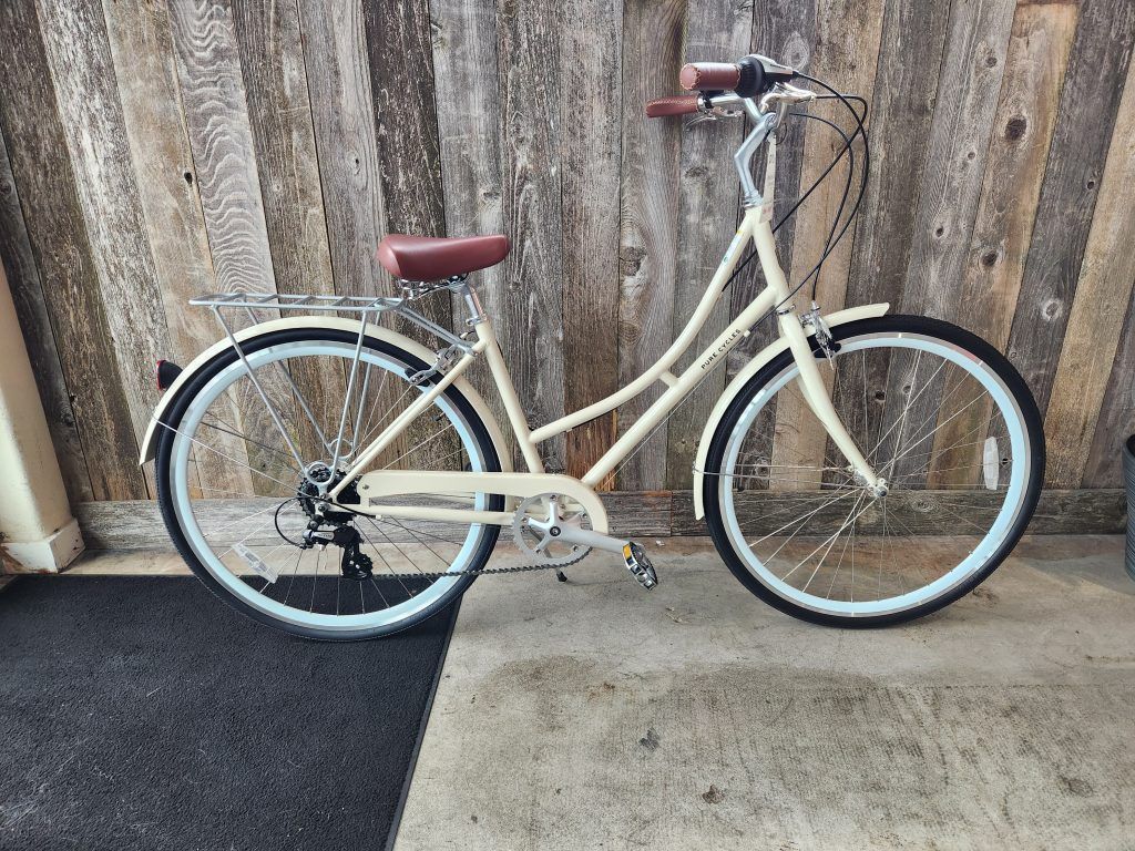 A white bicycle is parked in front of a wooden wall.