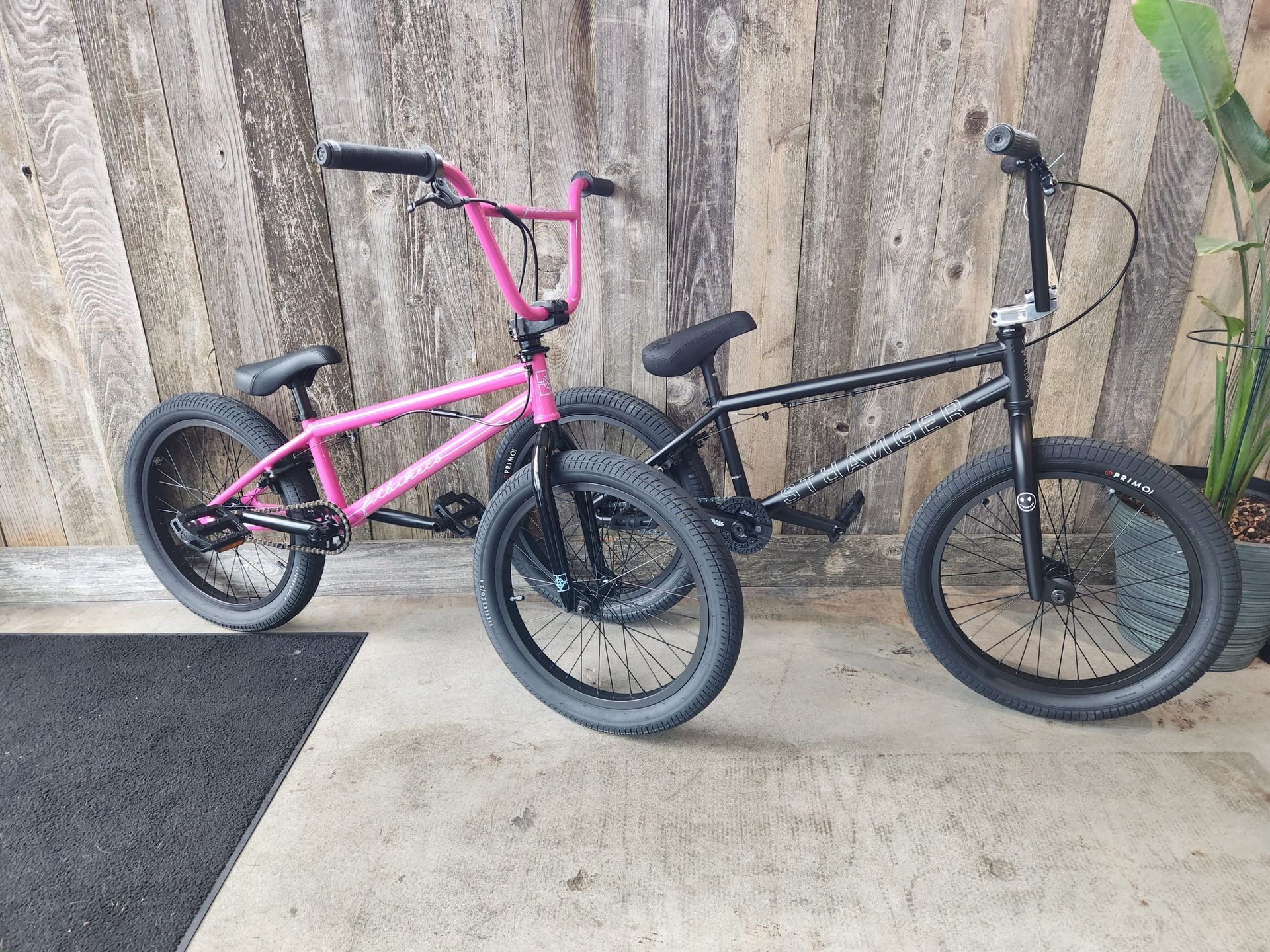 Two bmx bikes are parked next to each other on a sidewalk.