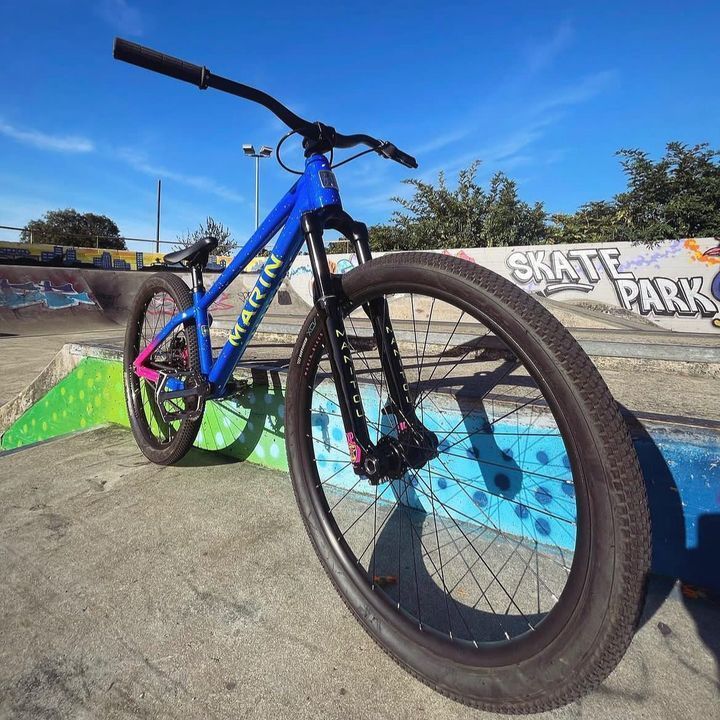 A blue bike is parked in front of a skate park