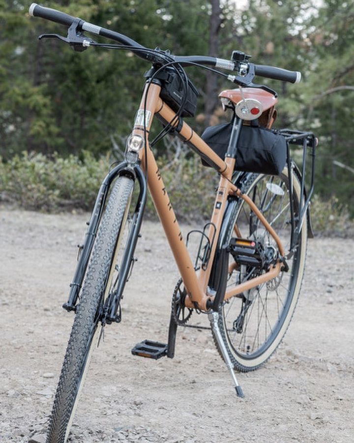 A brown bicycle is parked on a dirt road