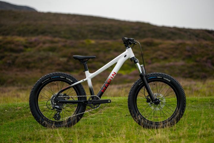 A white mountain bike is parked in a grassy field.
