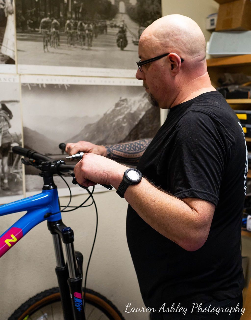 A man in a black shirt is working on a blue bicycle