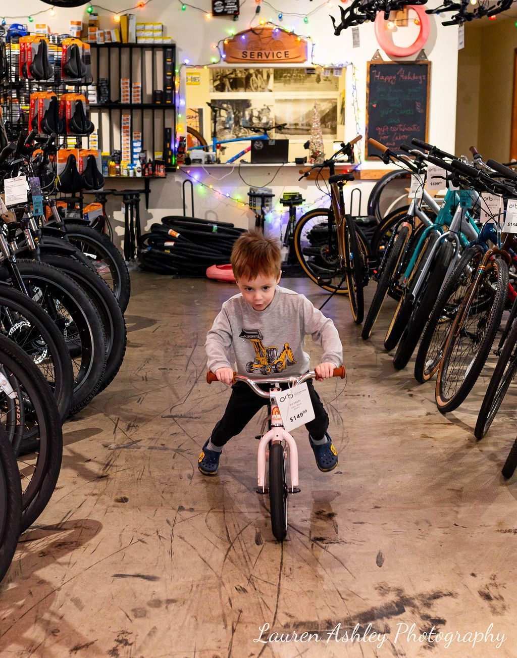 A little boy is riding a bike in a bicycle shop.
