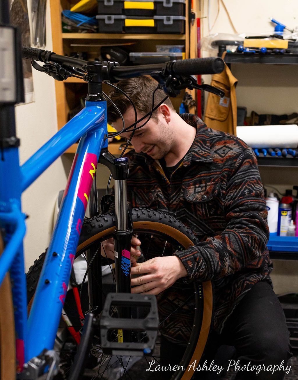 A man is working on a blue bicycle in a garage