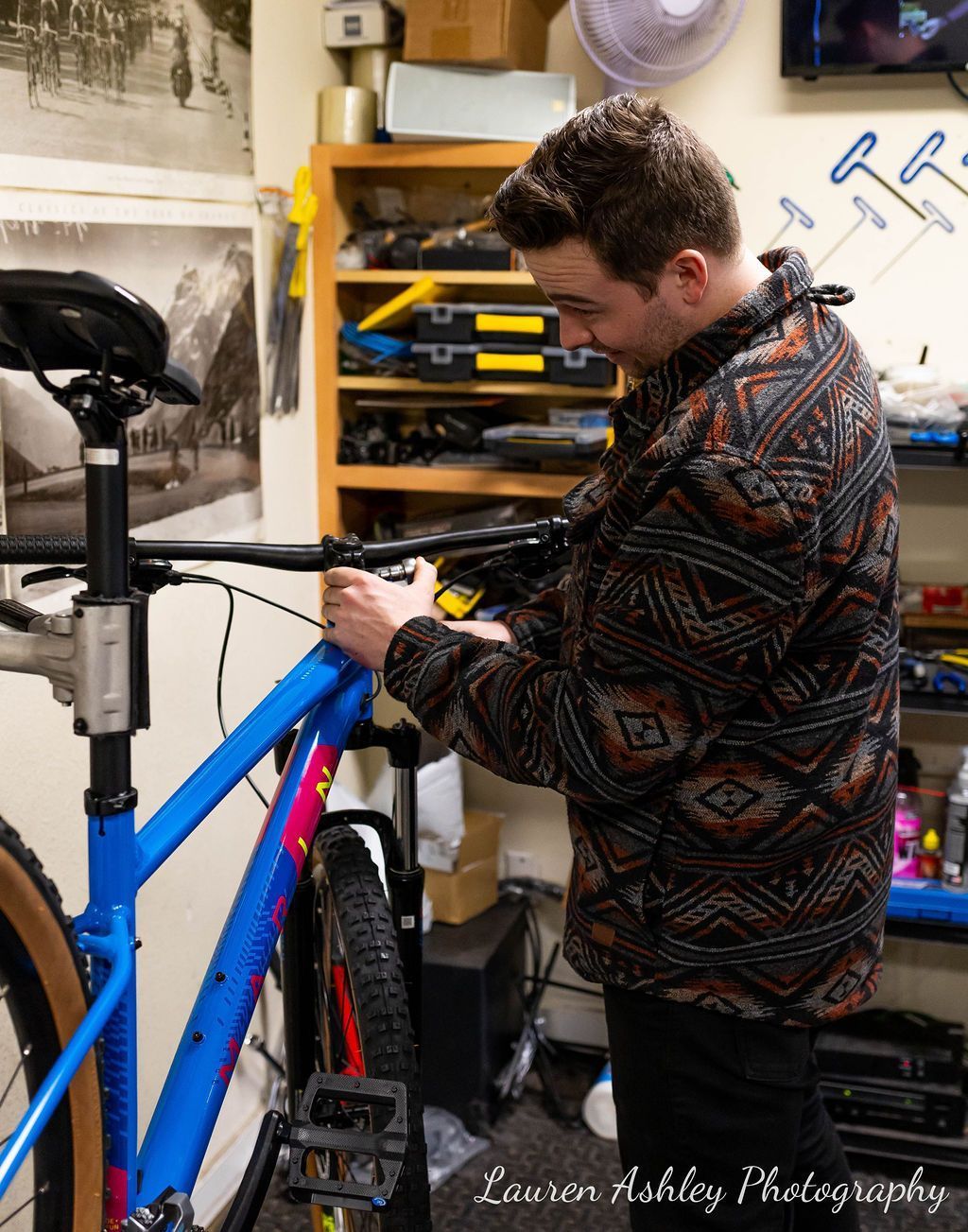 A man is working on a bicycle in a garage.