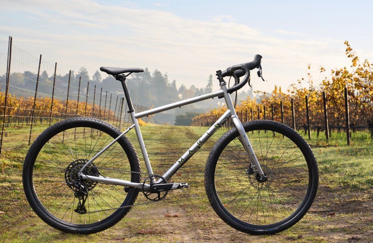 A bicycle is parked in the middle of a vineyard.