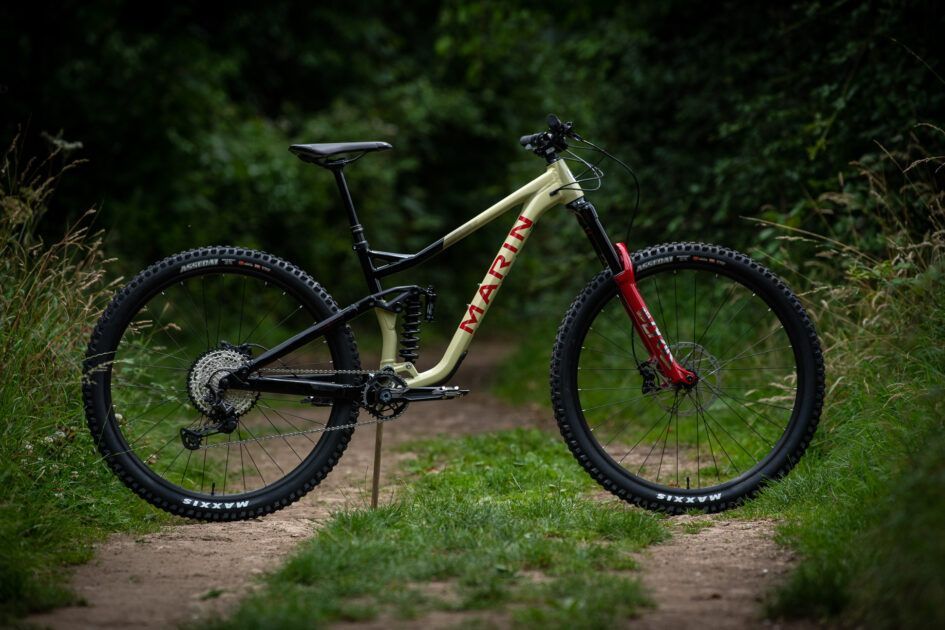 A mountain bike is parked on the side of a dirt road.