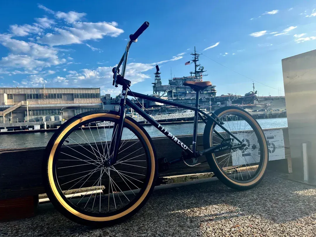 A bicycle is parked on the side of a road next to a body of water.